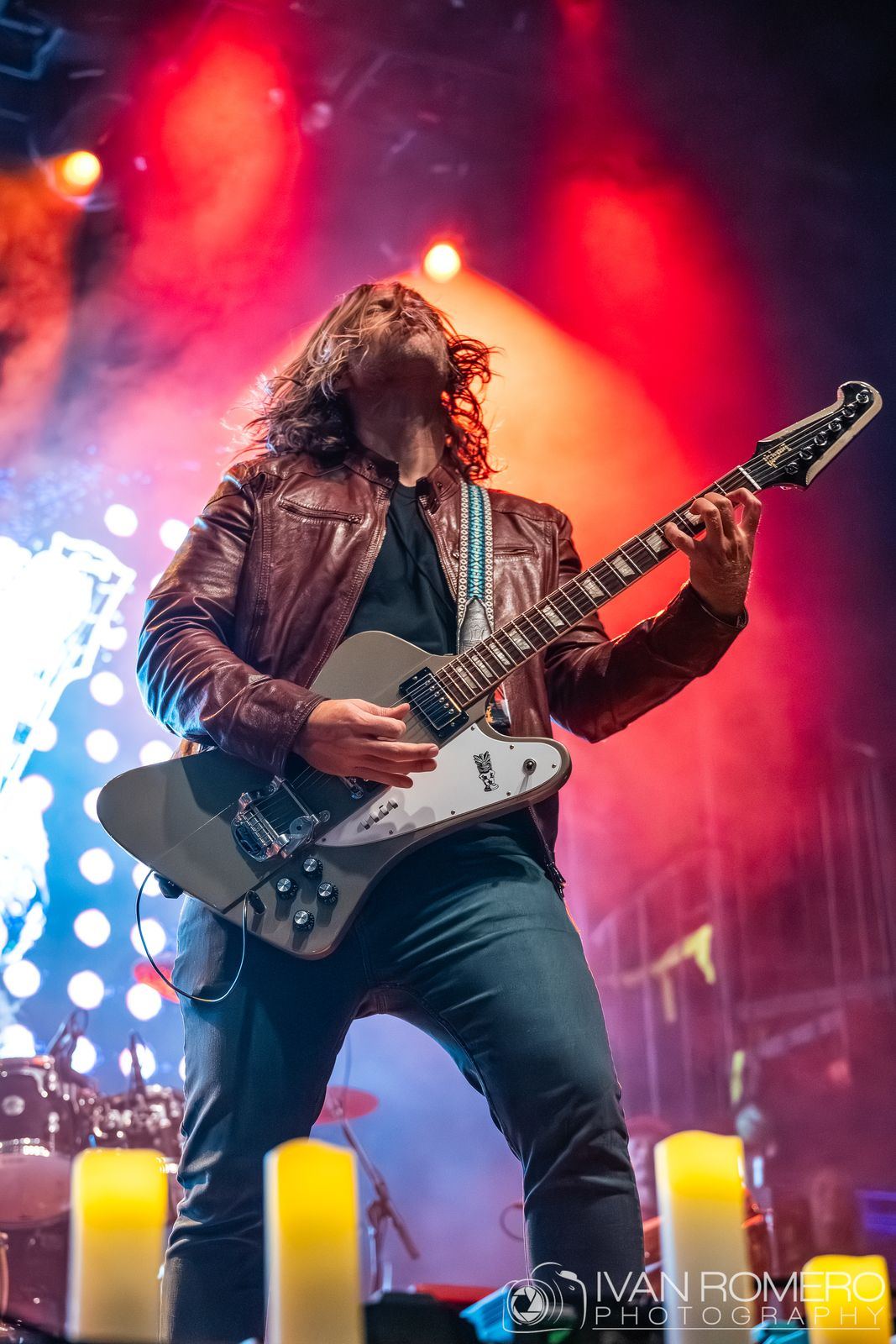 A guitarist behind the line of candles
