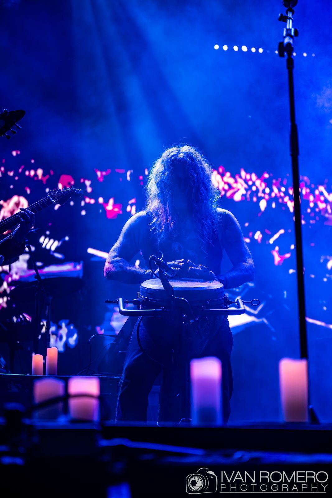 A keyboard player in blue light behind the row of candles