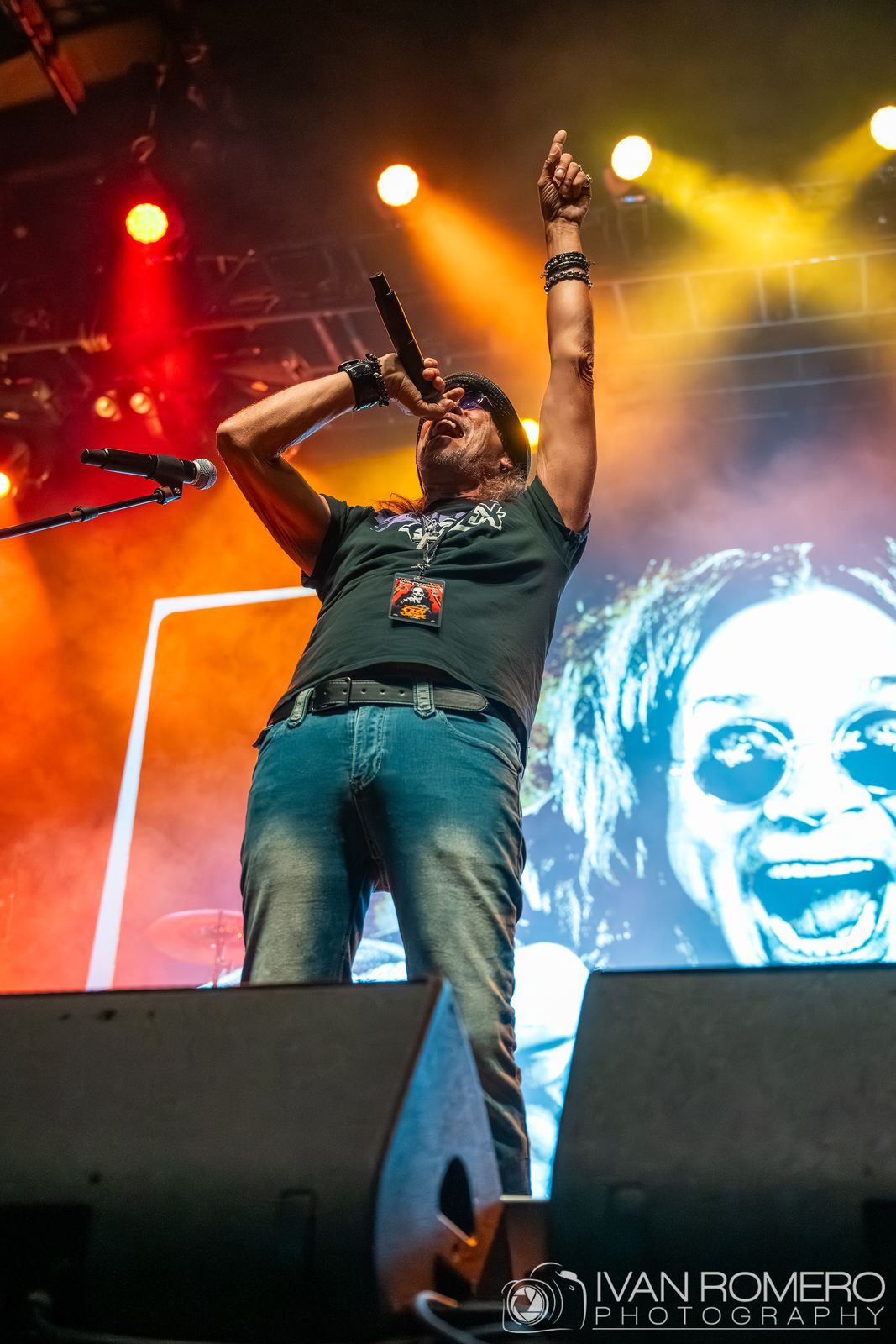 A singer pointing up in front of Ozzy on the screen