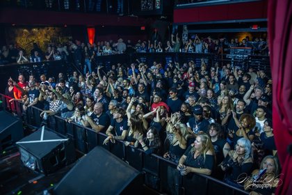 The audience, hands up at the barrier.