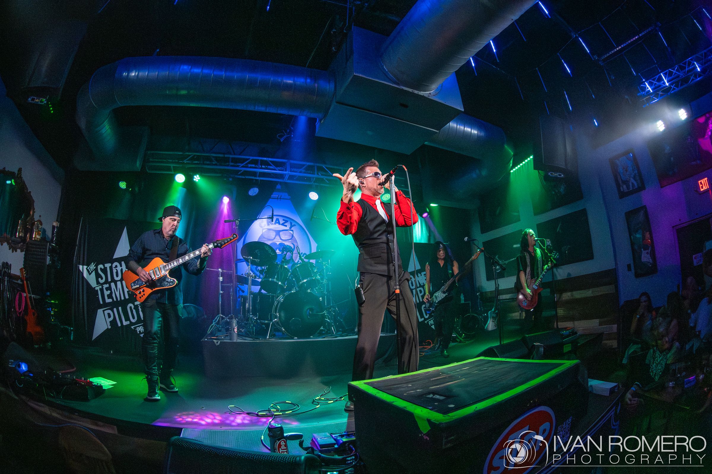 Wide shot of the band under colored beams at Crazy Uncle Mike’s