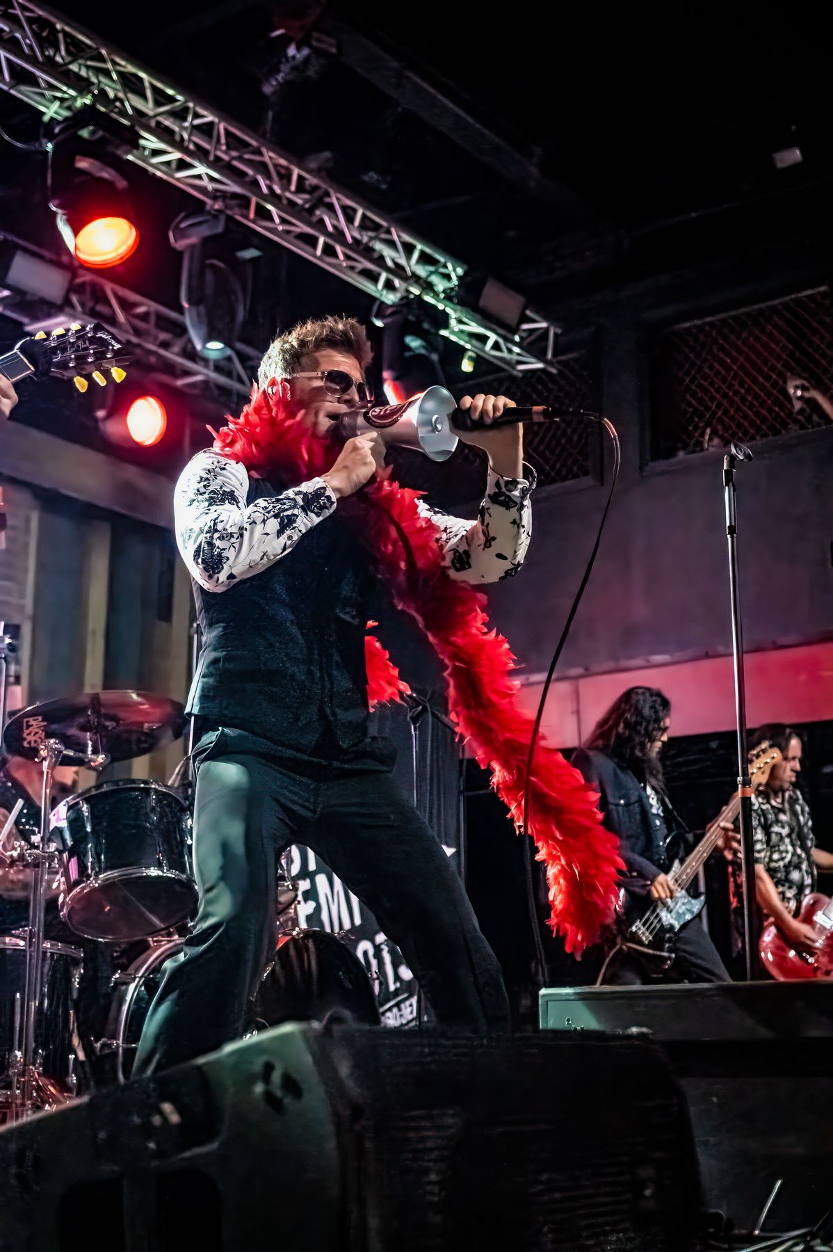 The singer in a red feather boa at the edge of the stage