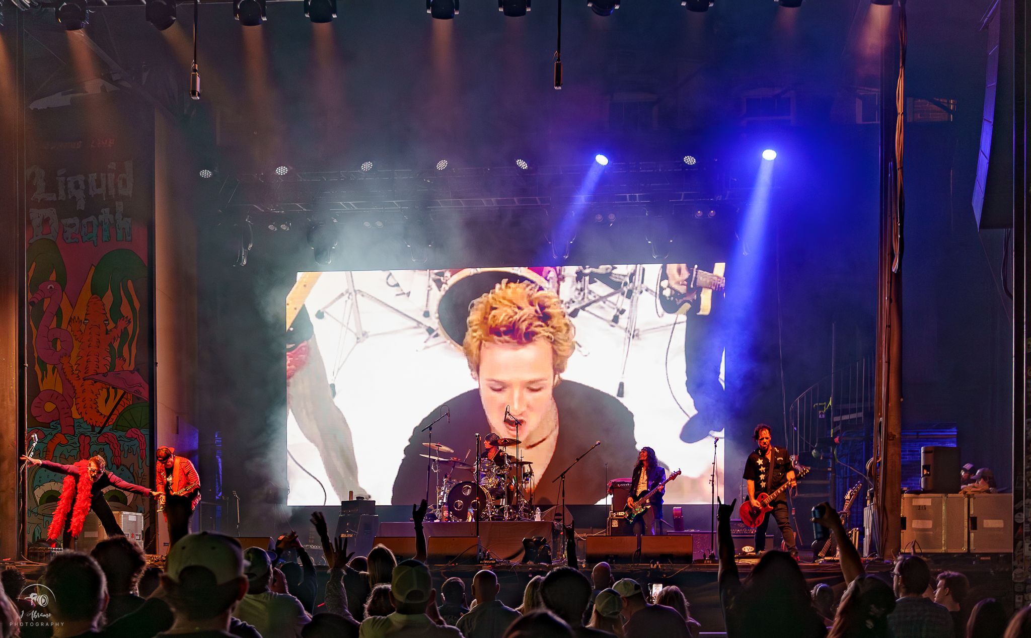An outdoor stage with the singer on the big LED wall above the band