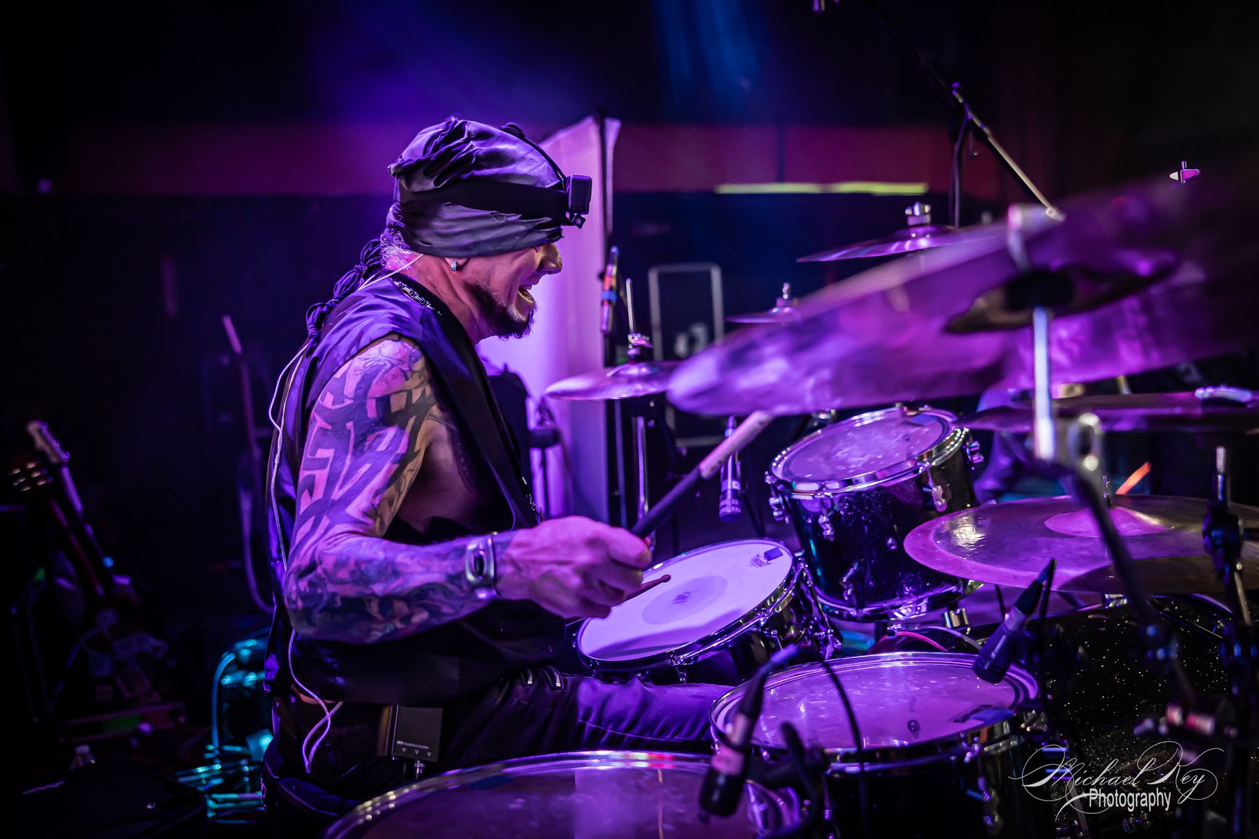 The drummer in purple light behind the kit