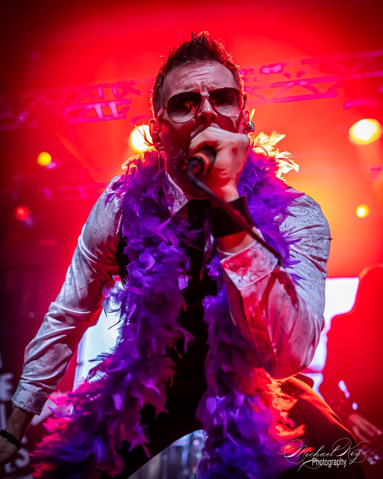 The singer in red light with a purple boa
